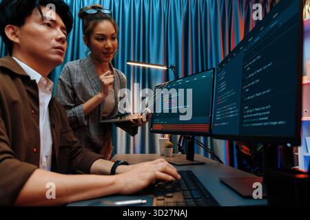 Serious of IT developers discussing intelligent website development coder system running data online two screens with laptop showing information netwo Stock Photo