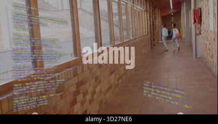 Walking two schoolgirls carrying backpacks in school corridor, with fire extinguisher, copy space Stock Photo