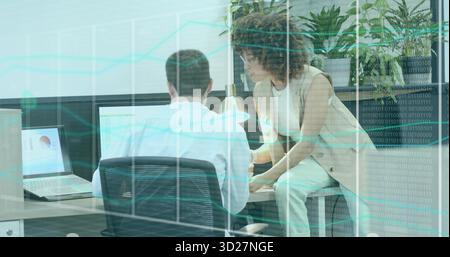 Office professionals reviewing data on computer screens in modern office, with laptops and plants Stock Photo