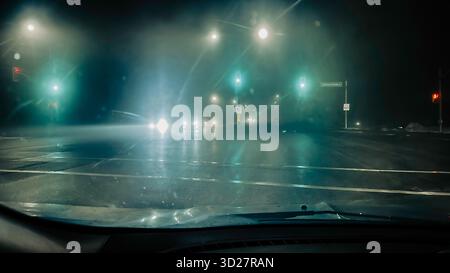 Road intersection at rainy night as seen from a car driver's point of view Stock Photo