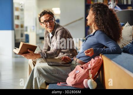Young Asian Man and Young Biracial Woman Studying Together and Smiling Indoors Stock Photo