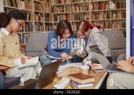 Multiethnic Group of Teenagers Collaborating on School Project in Library Stock Photo