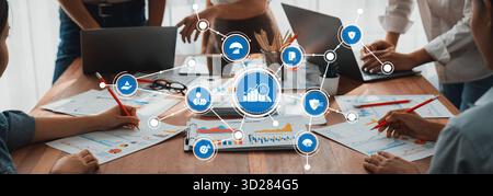 Engaging business management meeting showcasing teamwork and analytics. Collaborative professionals use laptops and papers to strategize and enhance p Stock Photo