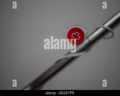 Emergency red nurse call button with medical cross symbol on hospital bed handle, close-up of healthcare assistance device in modern patient room . Hi Stock Photo