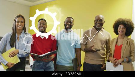 Collaborating team of five showing data graphic by yellow wall in office holding papers and devices Stock Photo