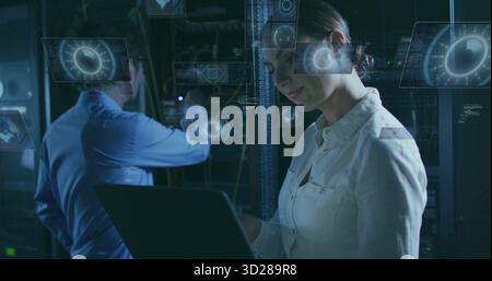 Reviewing engineer examining laptop in server room, holographic UI, network cables, copy space Stock Photo