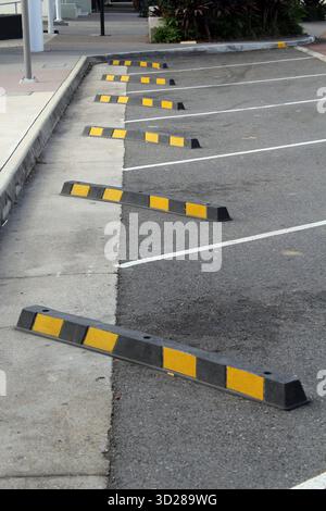 Series of yellow and black parking blocks stops on an asphalt road Stock Photo