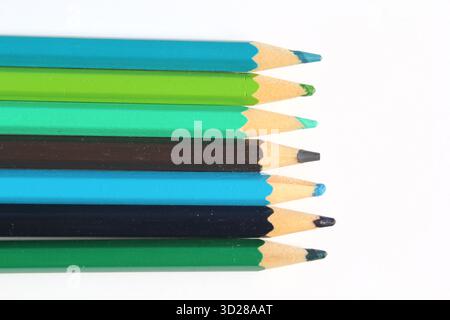 Row of blue and green colored pencils arranged on a white background Stock Photo