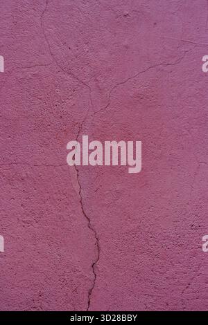 Pink plaster with a large crack. Close-up of a damaged concrete wall. Stock Photo