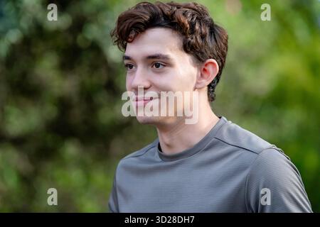 Handsome young man smiling with a thoughtful expression looking to the right outdoors Stock Photo