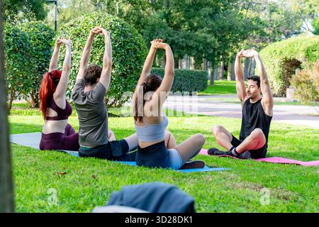 People stretching arms overhead during outdoor yoga class on grass Stock Photo