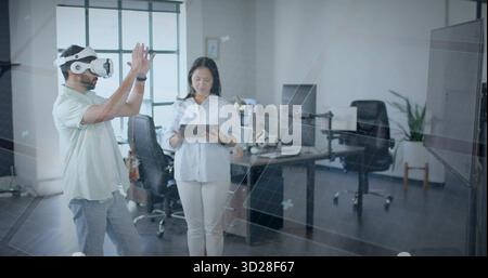 Colleagues manipulating interface in office near grid window, wearing VR headset and using tablet Stock Photo