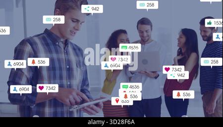 Collaborating professionals discussing social metrics on tablet and laptop in office with icons Stock Photo
