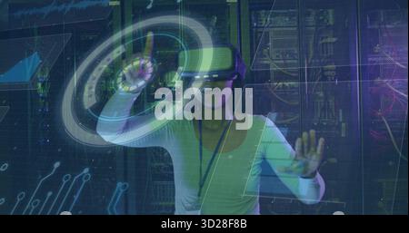 Manipulating holographic interface wearing VR headset at data center, with server racks and cables Stock Photo