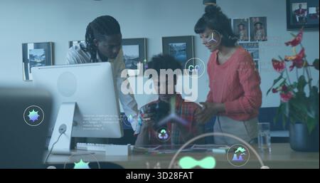 Collaborating three tech professionals coding with holographic icons at office desk, with tablet Stock Photo