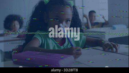 Writing girl wearing green T-shirt holding pencil over paper in classroom, with pink pencil case Stock Photo