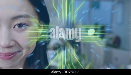 Smiling Chinese woman displaying neon-green AI overlay in office with desks and screens, copy space Stock Photo