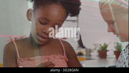 Holding component and discussing code, two girls at study table, with computer monitor and plants Stock Photo