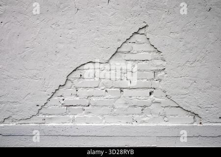 white painted brick wall with damaged plaster background Stock Photo