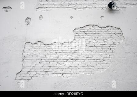 white painted brick wall with damaged plaster background Stock Photo