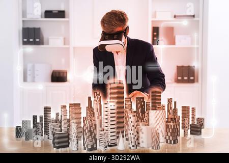 Man using virtual reality headset in office. Hologram of buildings in front of him. Modern technologies in architecture Stock Photo