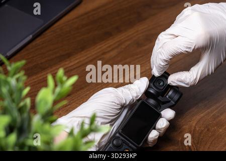 Poznan, Poland - October 16, 2025: Top-down view of DJI Osmo Pocket camera held by hands in white gloves, highlighting hygienic handling of advanced v Stock Photo