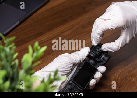 Poznan, Poland - October 16, 2025: Close-up of gloved hands precisely adjusting a DJI Osmo Pocket 2 camera, preparing for professional video recording Stock Photo