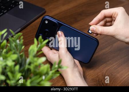 Poznan, Poland - October 16, 2025: iPhone 17 Pro, a new smartphone, displayed with hands inserting a SIM card, highlighting activation for mobile netw Stock Photo