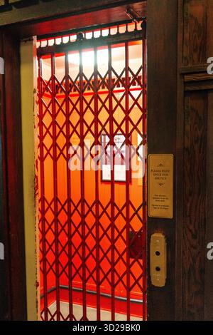 Prince of Wales, Waterton, AB, Canada - 08/11/2025: A vintage elevator with a red scissor gate and 'buzz for service' sign. Waterton, AB Stock Photo