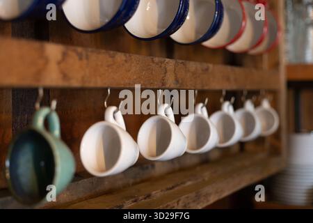 selective focus, many ceramic coffee mugs Hanging on a wooden wall In a country cafe Stock Photo