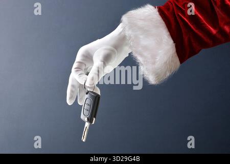 Santa Claus hand in glove suit holding a car electronic key isolated on blue background Stock Photo