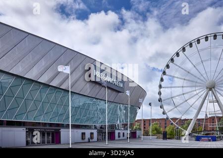 Modern M&S Bank Arena beside Wheel of Liverpool observation wheel on waterfront plaza under spring skies, contemporary architecture and entertainment Stock Photo