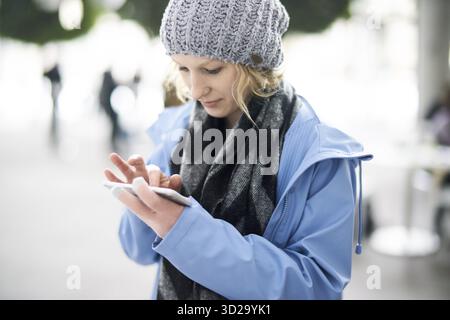 Preoccupied woman typing on smartphone, digital media internet connection, mobile phone, touchscreen, using application, wearing winter clothes like s Stock Photo