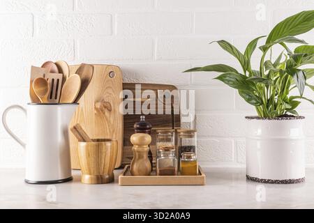 Beautiful kitchen background with spice storage area, cutting wooden boards, green plant in a chic indoor pot. white brick wall.. Front view Stock Photo