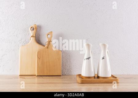 Kitchen background in a minimalist style. two cutting wooden boards and two ceramic special bottles of oil on a tray. Relief wall. Front view Stock Photo