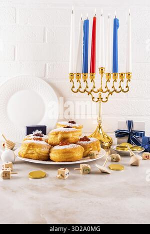 Traditional symbols, treats on a marble countertop against white brick wall. Burning candles in the Hanukkah menorah. vertical front view. still life Stock Photo