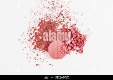 Round block, refill blush with a relief pattern of pink tone and a scattering of dry blush on a white background. texture, a sample of blush. top view Stock Photo