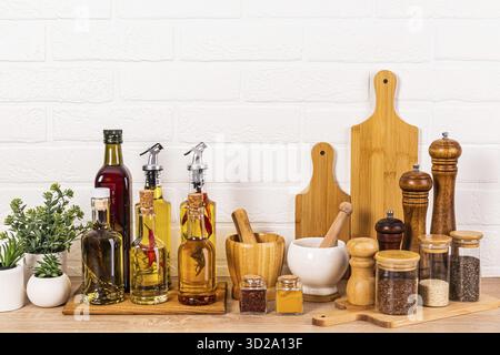 Stylish kitchen background with a set of bottles with various cooking oils, glass jars with spices, a set of kitchen tools. Front view Stock Photo