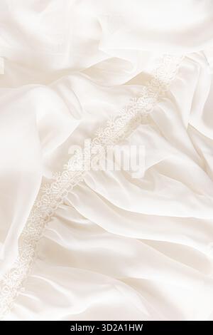 Details of chiffon beige fabric of the bride's dress with soft waves and lace. wedding background. elegant soft background texture. a copy space Stock Photo