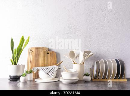 A set of various kitchen utensils and tools, ceramic dishes in light colors on a modern kitchen countertop. front view. a copy space Stock Photo