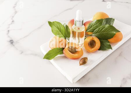 The perfect facial skin care product. apricot kernel oil in a cosmetic bottle with a pipette on a wooden white podium and a marble background Stock Photo