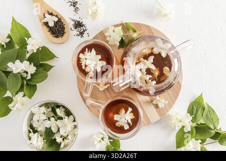 Beautiful tea composition with a modern teapot and cups with tea fragrant jasmine. top view. white textured background Stock Photo