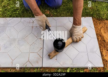 The master lays paving stones in layers. Garden brick pathway paving. Laying concrete paving slabs in house courtyard on sand foundation base Stock Photo