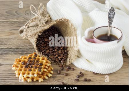 Cup of freshly brewed americano coffee with belgian waffles on wooden table. coffee beans on light wooden table, rustic style, homemade Stock Photo