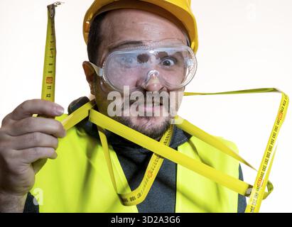 Juggling a man who wants to do a work without knowledge, work without experience. Do it yourself, man dressed in yellow builder helmet with protective Stock Photo