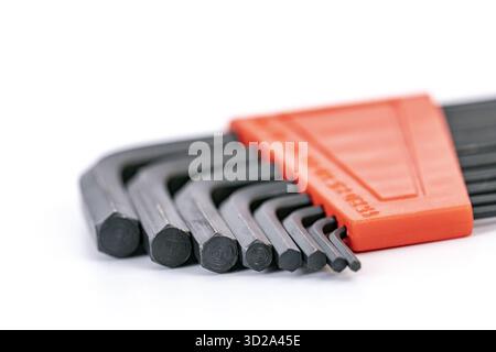 A close-up view of a hex key set arranged in an orange holder, showing different sizes of L-shaped made of black steel, used for tightening Stock Photo