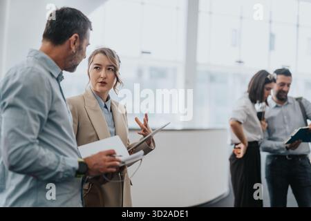 Professional woman leads discussion with colleague in a modern office, colleagues collaborate and review documents Stock Photo