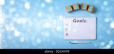 New 2026 Year Goals. Inscription in notebook and cubes with numbers on light blue background, top view. Bokeh lights Stock Photo