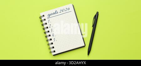 New 2026 Year Goals. Inscription in notebook and pen on light green background, top view. Banner design Stock Photo
