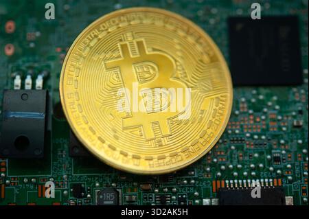 physical Bitcoin coin placed on computer motherboard representing cryptocurrency mining and blockchain technology Stock Photo